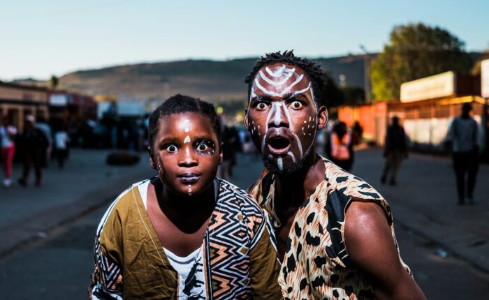 two people with face paints taking photo in street